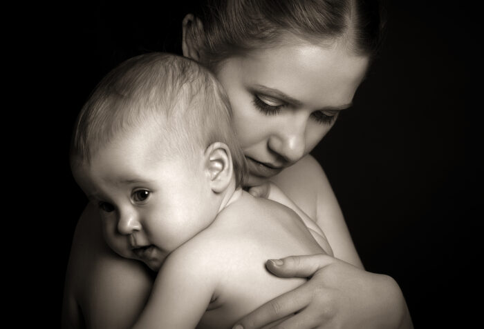 Mother holding a baby over a black background.