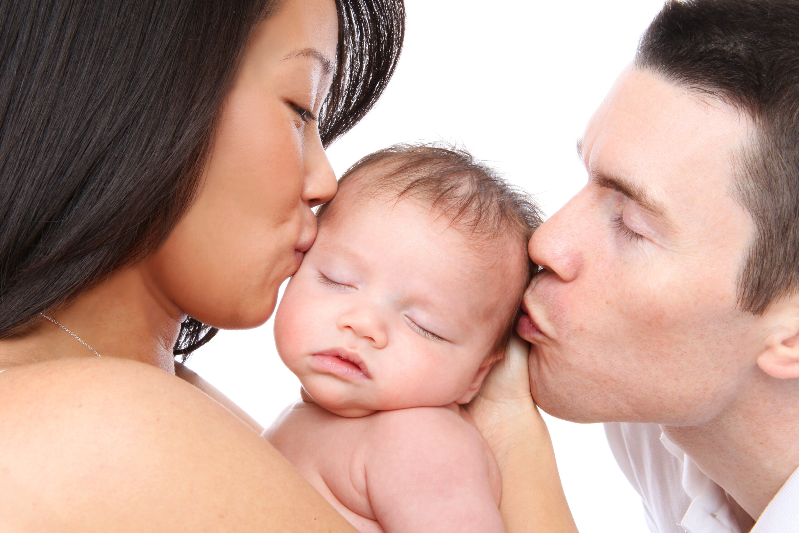 Parents Kissing Baby A mother and father both kissing their newborn baby.