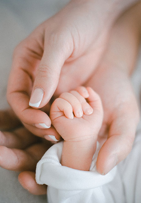 adult hands holding an infant hand
