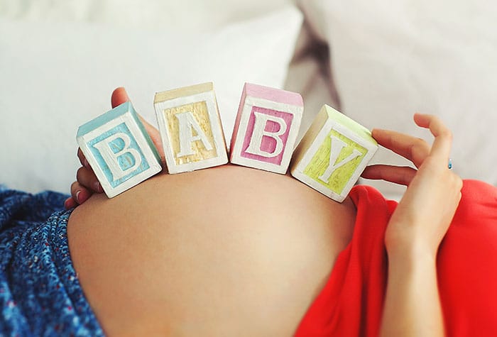 Pregnant belly with blocks on it that spell out "baby"