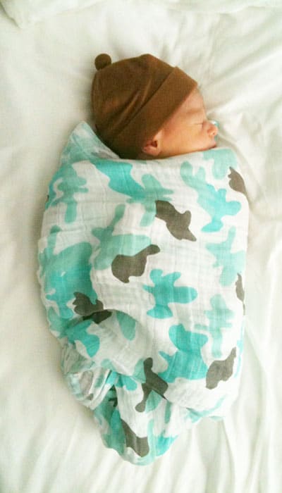 Newborn baby swaddled in a blanket and wearing a hat.